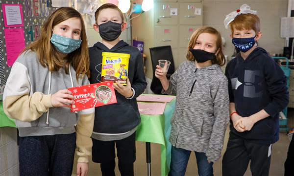 Students hold up science experiment supplies